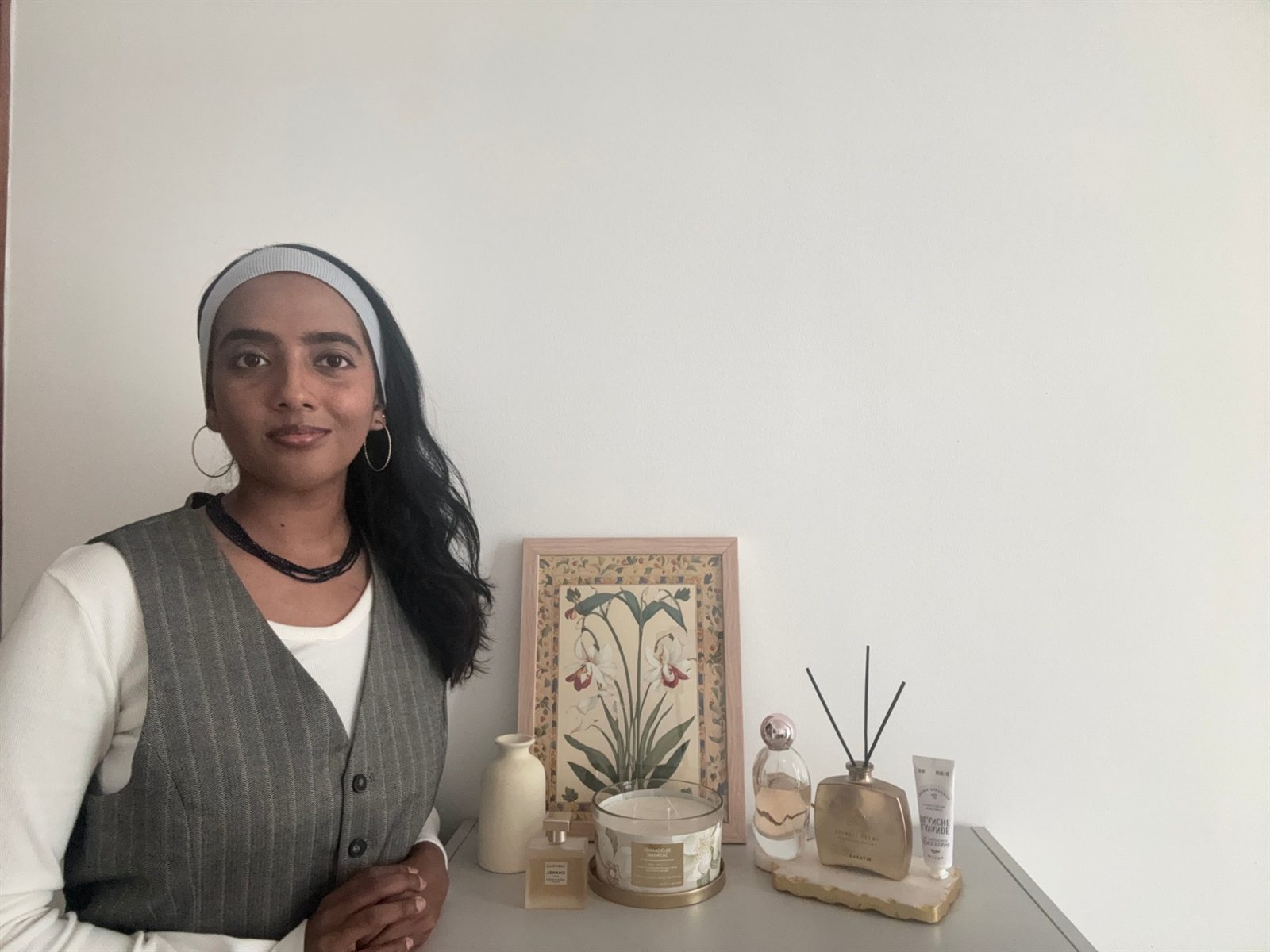 Portrait of Abigail Nargunam next to her fragrance shelf